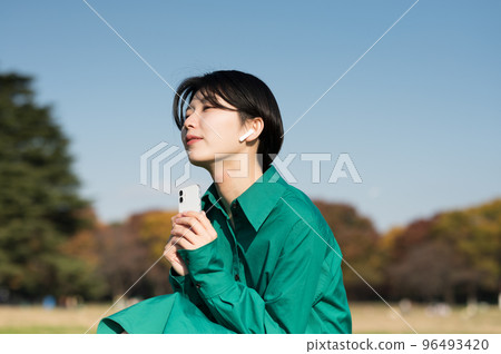 Woman enjoying music outdoors Woman enjoying music outdoors 96493420