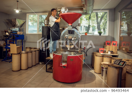 Experienced employee adding a product into the roasting machine Experienced employee adding a product into the roasting machine 96493464