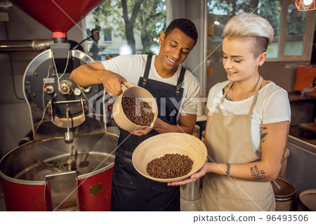 Joyful young couple of roast masters working together Joyful young couple of roast masters working together 96493506
