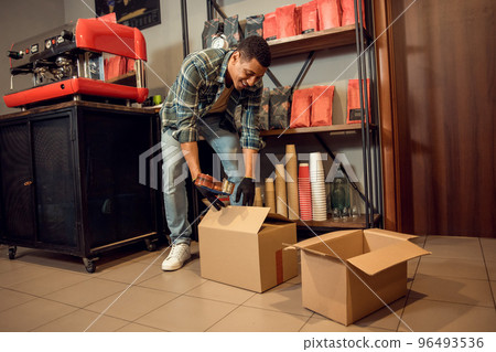 Cheerful coffee shop worker preparing wares for shipment 96493536