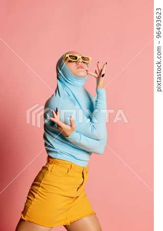 Weird people concept. Creative portrait of young girl in avant-garde fashion style outfit posing isolated over pink background. Vivid style, queer, art, fashion 96493623
