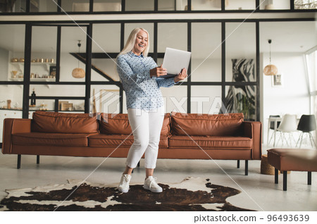 Blonde woman with a laptop feeling excited and happy Blonde woman with a laptop feeling excited and happy 96493639