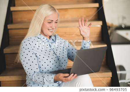 Blonde woman with a laptop looking involved and contented Blonde woman with a laptop looking involved and contented 96493705