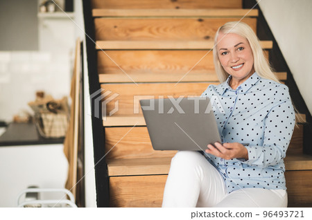 Blonde woman with a laptop looking involved and contented Blonde woman with a laptop looking involved and contented 96493721