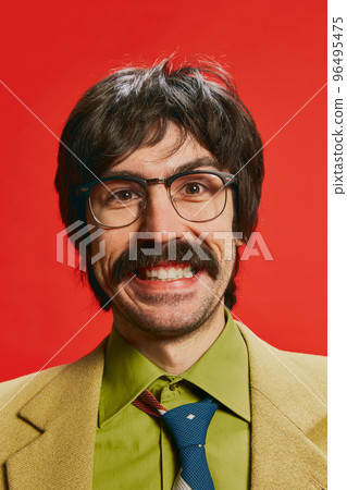 Close-up portrait of man with moustache posing in vintage suit and glasses isolated over red background. Happy 96495475