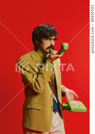Portrait of stylish man with moustache, businessman in vintage suit talking on phone isolated over red background 96495501