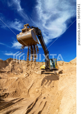 Yellow excavator working with sand at construction site 96495641