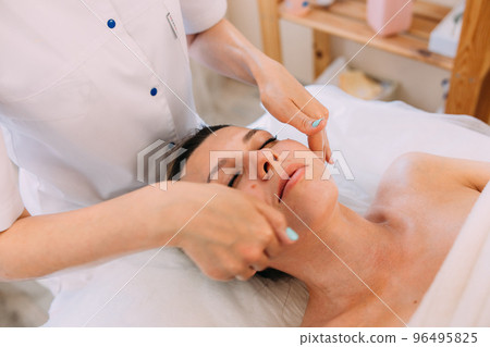 Cosmetologist does facial massage for woman. Beauty skin care 96495825