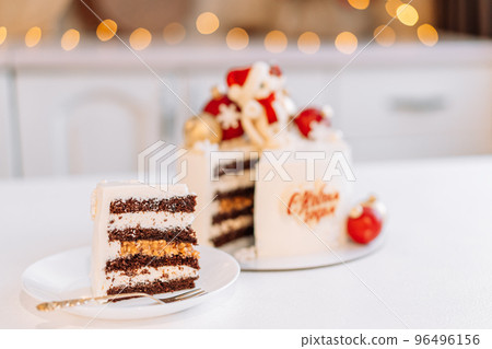 White Christmas cake with caramel bunny and balls in front of the lights from the garlands White Christmas cake with caramel bunny and balls in front of the lights from the garlands 96496156