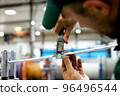 factory worker in a robe and cap checks the performance of the device for the production of cable products from a copper core 96496544