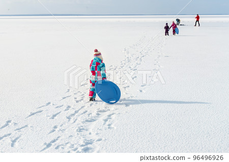 Two cute adorable funny sibling kid friend wear warm jacket enjoy have fun sledging with saucer at frozen white snow lake edge against clean blue sky horizon landscape bright sunny cold winter day Two cute adorable funny sibling kid friend wear warm jacket enjoy have fun sledging with saucer at frozen white snow lake edge against clean blue sky horizon landscape bright sunny cold winter day 96496926