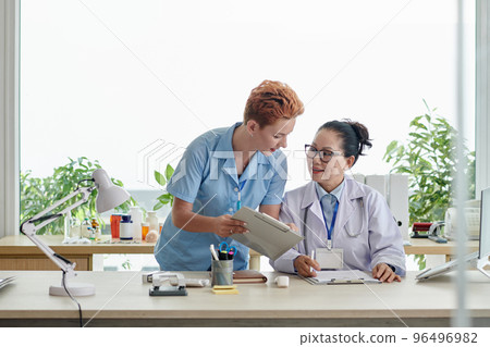 Medical nurse asking doctor to sign document Medical nurse asking doctor to sign document 96496982