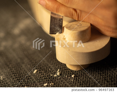 luthier artisan maker sculpting and carving violin scroll and neck with chisel 96497163