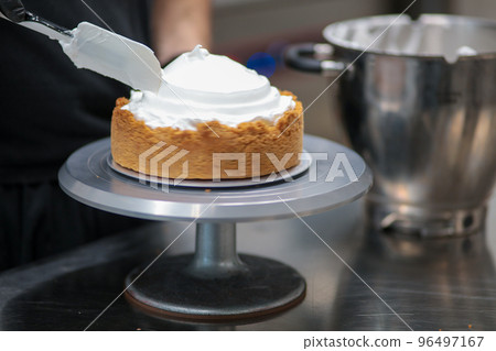 pastry chef designer filling a pie crust with lemon flavour meringue mousse cheese cream with spatula 96497167