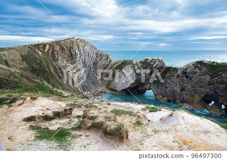 Beautiful view of Stair Hole, small cove to the west of Lulworth Cove in Dorset, Untited Kingdom. View of rock formations and nature made caves and blue sea, selective focus Beautiful view of Stair Hole, small cove to the west of Lulworth Cove in Dorset, Untited Kingdom. View of rock formations and nature made caves and blue sea, selective focus 96497300