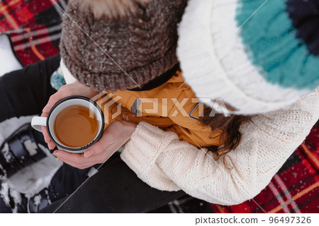 Mother and child on a winter walk outdoors drinking tea Mother and child on a winter walk outdoors drinking tea 96497326