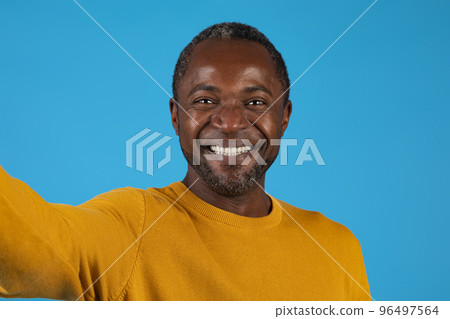 Closeup of happy handsome black man taking selfie on blue Closeup of happy handsome black man taking selfie on blue 96497564