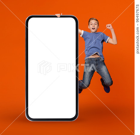 Online Ad. Surprised Teen Boy Holding Huge Blank Smartphone And Jumping 96497678