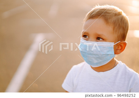 Little boy in medical face mask in the city. Virus and illness protection. Covid-2019. Kids safety. Little boy in medical face mask in the city. Virus and illness protection. Covid-2019. Kids safety. 96498252