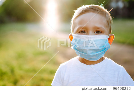 Portrait of little boy with medical face mask in the park during pandemic. Concept of health. Covid-2019. Portrait of little boy with medical face mask in the park during pandemic. Concept of health. Covid-2019. 96498253