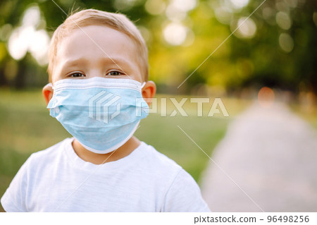 Portrait of little boy with medical face mask in the park during pandemic. Concept of health. Covid-2019. Portrait of little boy with medical face mask in the park during pandemic. Concept of health. Covid-2019. 96498256