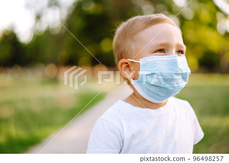 Portrait of little boy with medical face mask in the park during pandemic. Concept of health. Covid-2019. Portrait of little boy with medical face mask in the park during pandemic. Concept of health. Covid-2019. 96498257