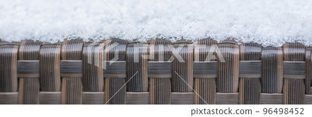 Care and storage of garden furniture in winter. texture of street furniture in winter. Artificial rattan covered with snow close-up. 96498452