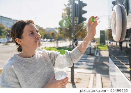 Woman uses a self service machine to receive used plastic bottles  96499465