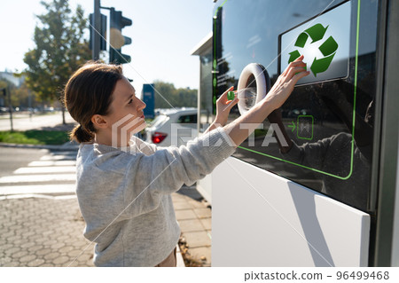 Woman uses a self service machine to receive used plastic bottles  96499468
