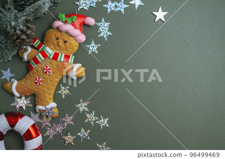 Christmas green background. Fir tree branches, seasonal ornament candy canes, ginger bread man. Creative flat lay, top view copy space 96499469