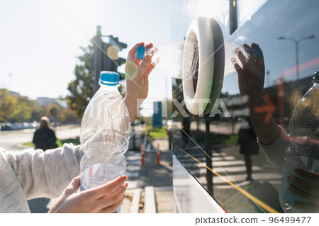 Woman uses a self service machine to receive used plastic bottles  96499477