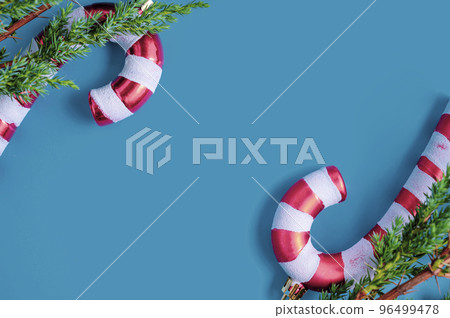 Christmas background. Fir tree branches, seasonal ornaments candy canes, stars. Creative blue flat lay, top view copy space 96499478