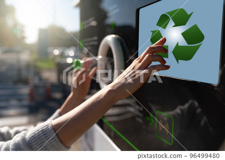 Woman uses a self service machine to receive used plastic bottles  96499480