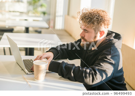Close-up male guy portrait resting in coffee shop chatting in social networks skilled freelancer enjoying remote job typing publication for web blog on laptop 96499493