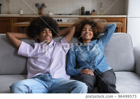 Peaceful African couple relaxing on sofa indoor Peaceful African couple relaxing on sofa indoor 96499573