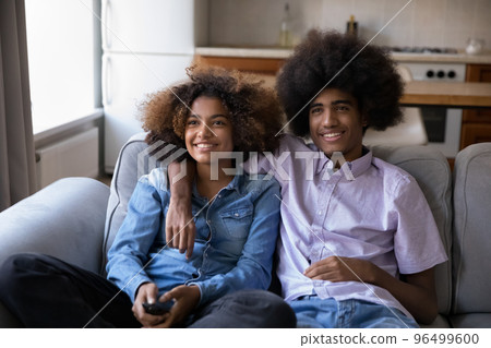 Teenager African couple resting on sofa enjoy movie at home 96499600