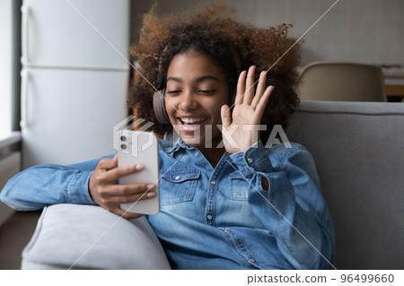African girl in headphones greets friend start videocall using smartphone African girl in headphones greets friend start videocall using smartphone 96499660