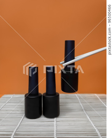 Black bottles of nail polish on a orange background Black bottles of nail polish on a orange background 96500466