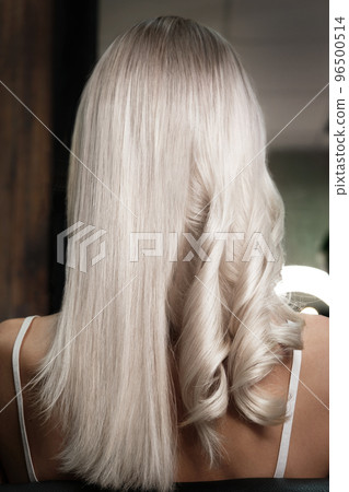 Young woman in a hairdressing salon dyes her hair blond and twists curls Young woman in a hairdressing salon dyes her hair blond and twists curls 96500514