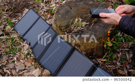 Hands plug in portable solar panel charging power bank by mutlipurpose cable, smartphone, watches, laptops nature background. Clean energy for using in camping or at home when NO electricity. Hands plug in portable solar panel charging power bank by mutlipurpose cable, smartphone, watches, laptops nature background. Clean energy for using in camping or at home when NO electricity. 96500842