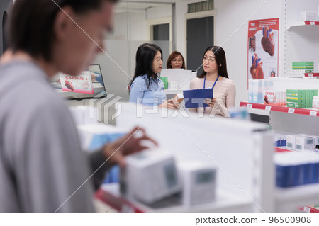 Team of asian women talking about prescription medicine, consultant giving medical advice about pharmaceutical supplements to client. Customer and worker analyzing pills package. Team of asian women talking about prescription medicine, consultant giving medical advice about pharmaceutical supplements to client. Customer and worker analyzing pills package. 96500908
