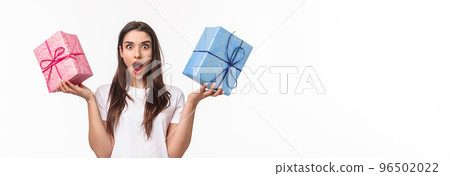 Celebration, holidays and presents concept. Portrait of excited and astounded, amazed young girl receive two awesome wrapped gift boxes, wander whats inside, stand white background surpised Celebration, holidays and presents concept. Portrait of excited and astounded, amazed young girl receive two awesome wrapped gift boxes, wander whats inside, stand white background surpised 96502022