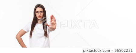 Waist-up portrait of serious-looking displeased confident young woman in glasses, activist or human-rights supporter pull palm forward to stop something bad, frowning disagree, prohibit action 96502251