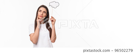 Entertainment, fun and holidays concept. Portrait of thoughtful and creative young woman searching inspiration, holding thinking cloud near head, squinting and look focused up, pondering 96502279