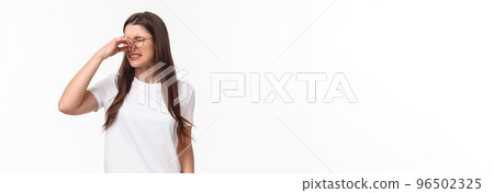 Smells disgusting. Portrait of disgusted and displeased young beautiful girl in glasses, shut nose with fingers and look away with grimace as something have awful smell, reek, stand white background Smells disgusting. Portrait of disgusted and displeased young beautiful girl in glasses, shut nose with fingers and look away with grimace as something have awful smell, reek, stand white background 96502325