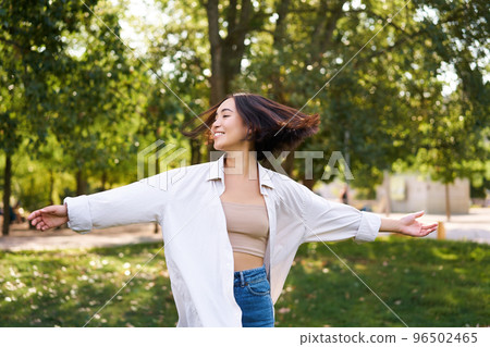 Freedom and people concept. Happy young asian woman dancing in park around trees, smiling and enjoying herself 96502465