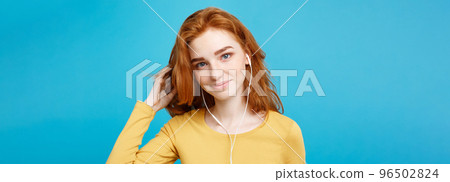 Lifestyle concept - Portrait of cheerful happy ginger red hair girl enjoy listening to music with headphones joyful smiling to camera. Isolated on Blue Pastel Background. Copy space. 96502824