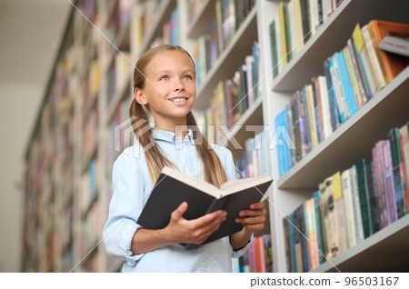Cute girl searching for a book in the school library 96503167