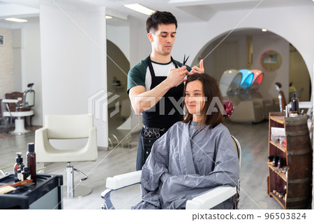 Man doing haircut for woman in salon 96503824