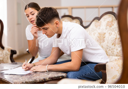 Young couple is studying the documents and signing them 96504010